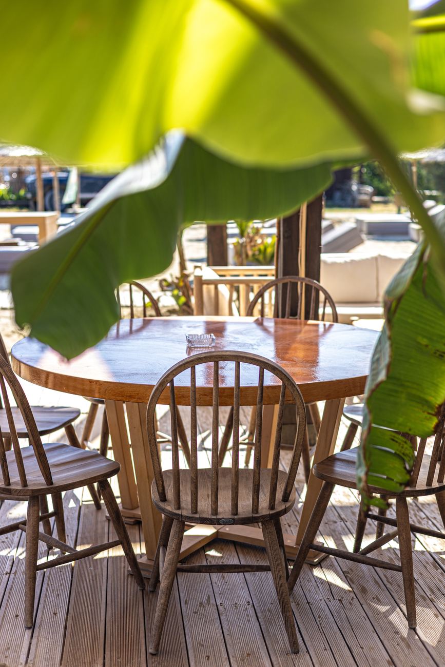 Wooden table and chairs under a banana leaf